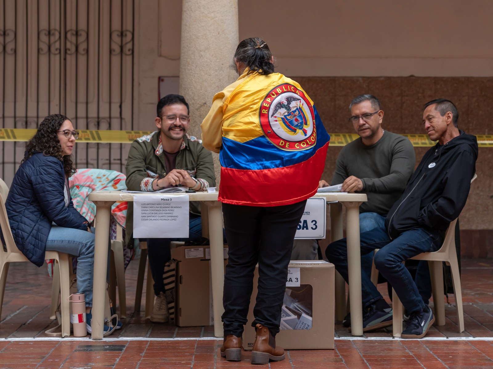 A voter wearing a Colombian flag registers to cast a ballot during Colombia's 2026 presidential runoff.