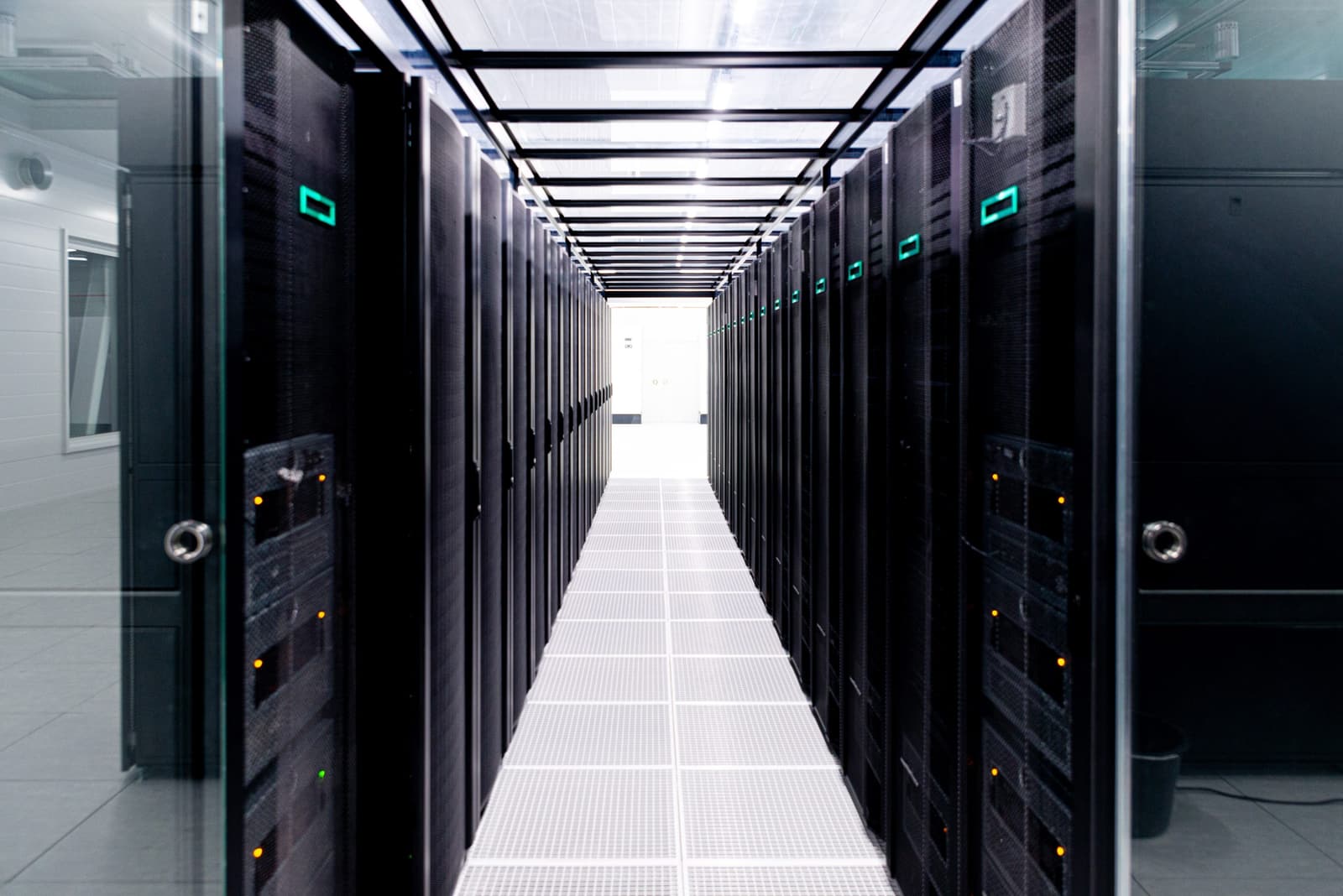 A photographic view down an aisle of black LUMI supercomputer cabinets in a bright data center.
