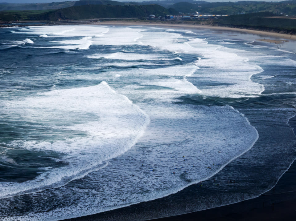 A beach in Asturias, Spain, with visible dark gaps and different wave sets associated with rip currents.