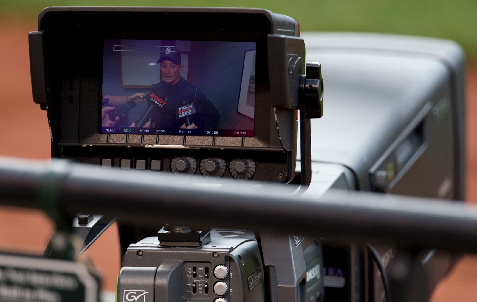 A real photograph of a professional video camera monitor showing a person framed inside the display.