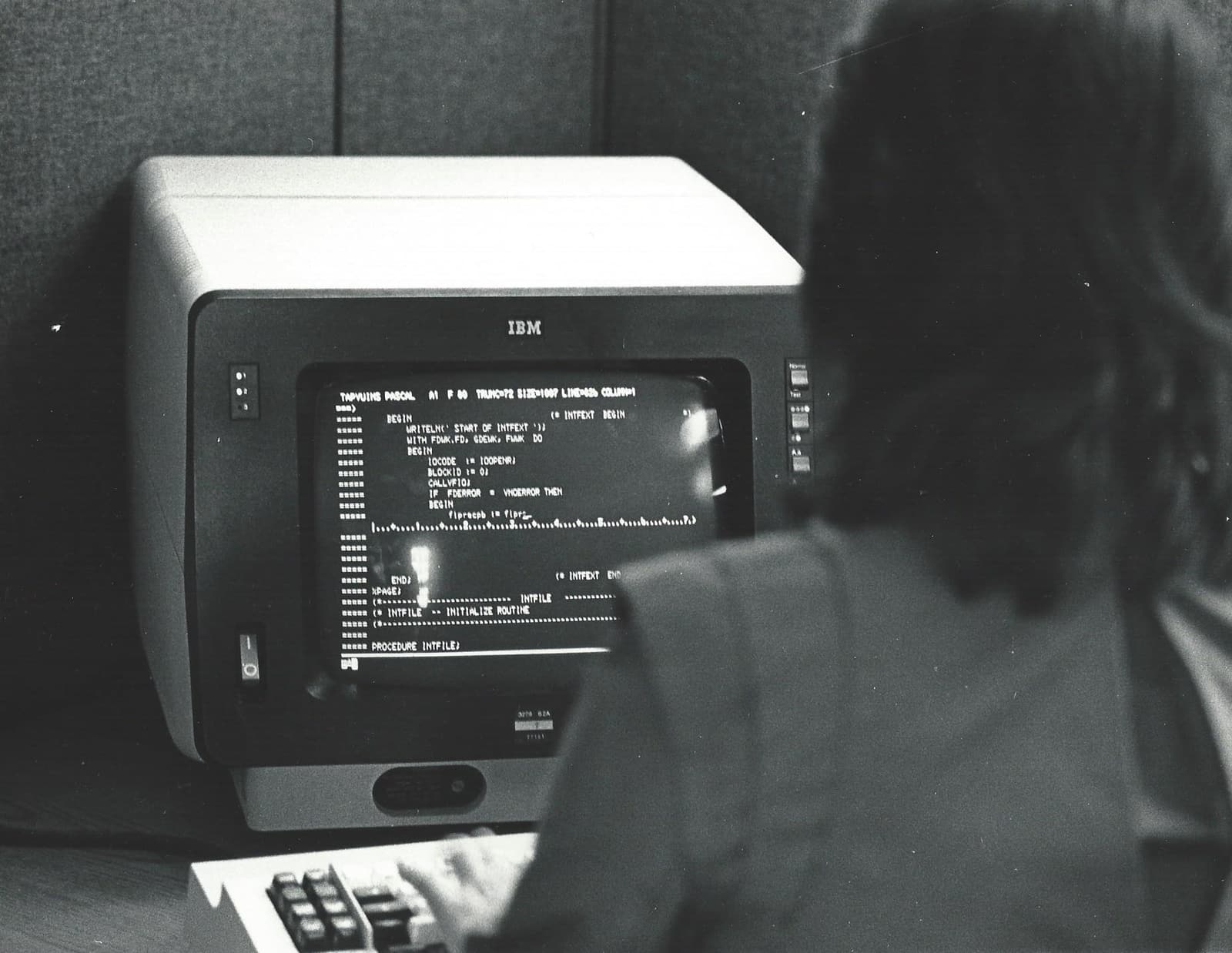 A programmer at an IBM 3270 terminal in a 1983 New York office cubicle.