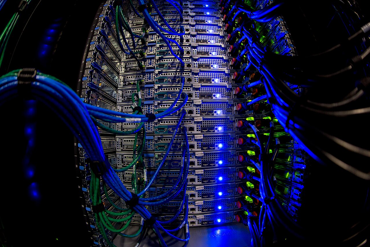 A Wikimedia Foundation server rack filled with blue and green network cables and rows of lit servers.
