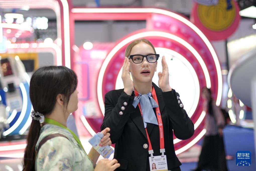 在海南举行的中国国际消费品博览会上，一名科大讯飞员工为参观者演示 AI 眼镜。