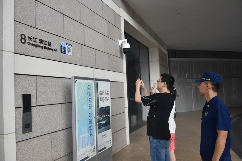 在重庆市渝中区，一名男子扫描贴在建筑外墙上的高层建筑消防码，一名身着制服的消防员在旁观察。