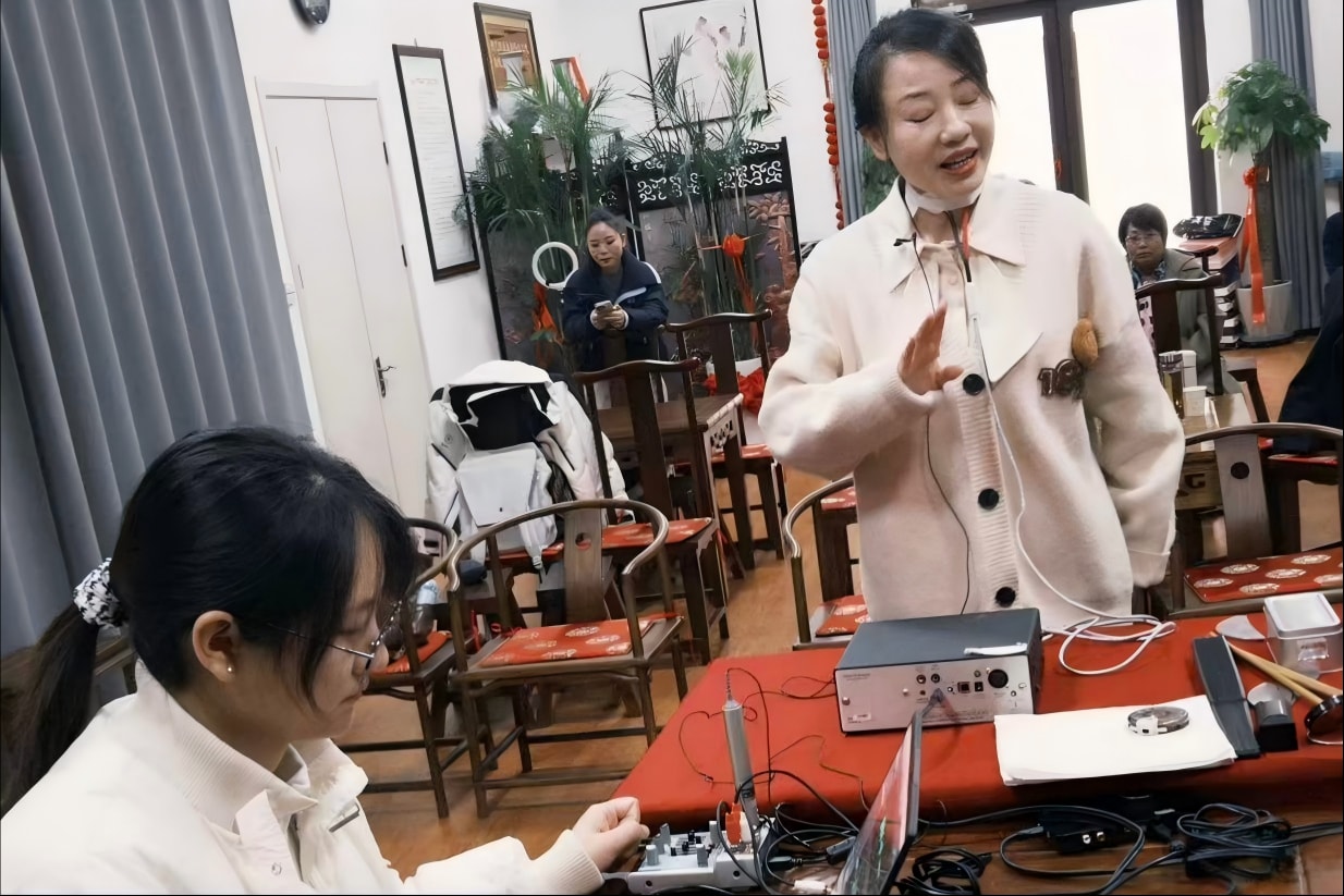 曹县方言田野调查中，连接着录音设备的一名女性正在讲话，研究人员操作音频接口和笔记本电脑。