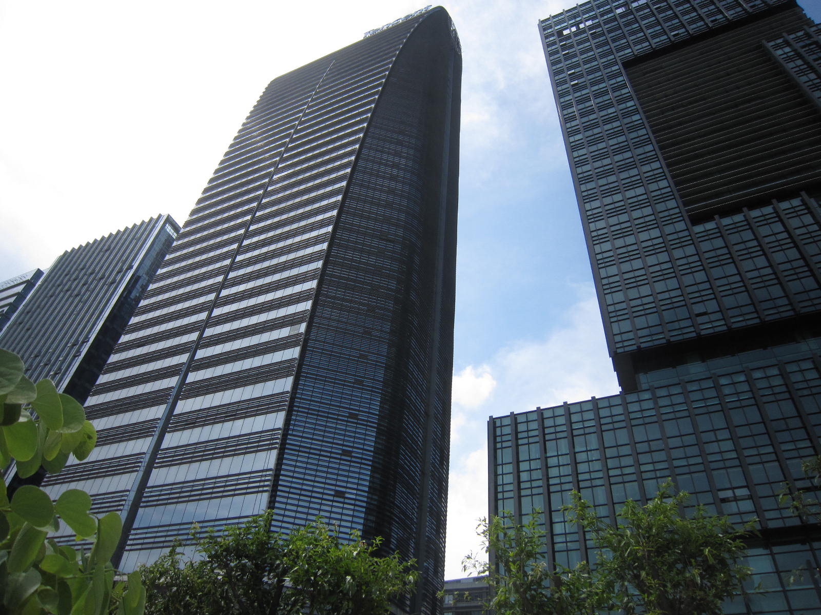 Low-angle photograph of Tencent's headquarters building in Shenzhen, with glass towers rising above trees.