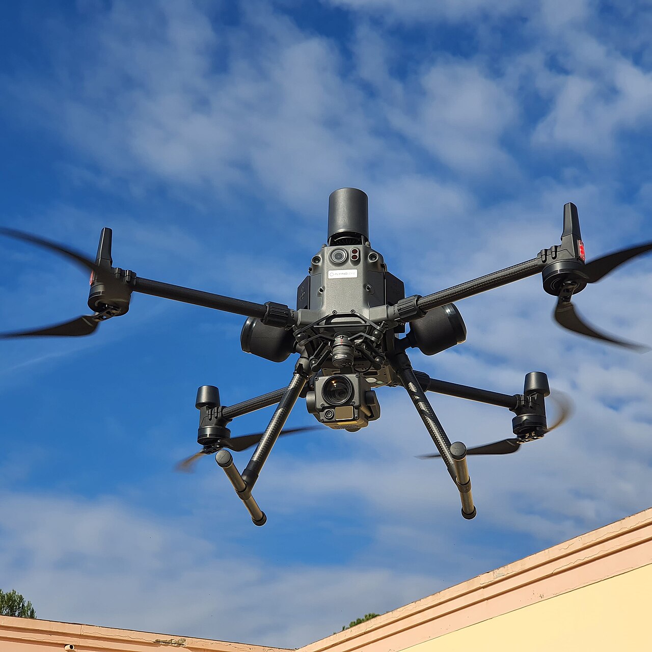 Photograph of a DJI Matrice 300 RTK enterprise drone hovering against a blue sky.