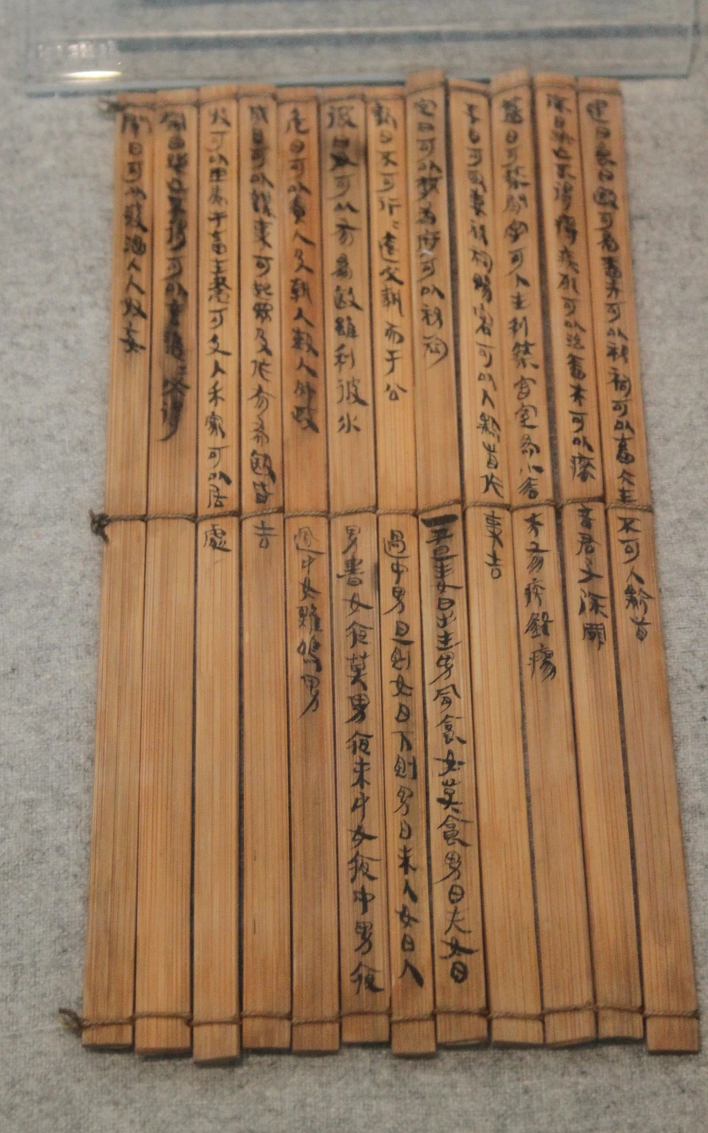 Inscribed bamboo slips tied in two rows and displayed behind glass at the Changsha Jiandu Museum.