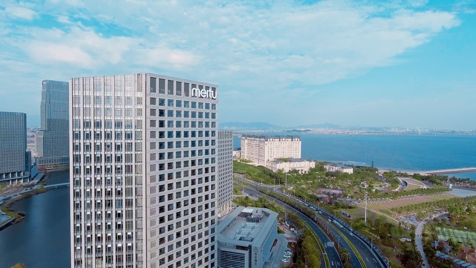 Aerial photograph of Meitu's headquarters building in Xiamen beside the water.