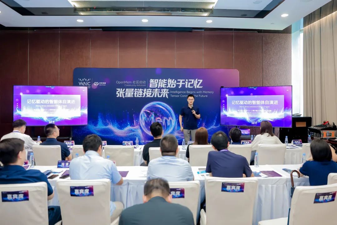 MemTensor 的 OpenMem 社区启动活动上，一位演讲者面对落座观众发言，身后是紫色会议屏幕。
