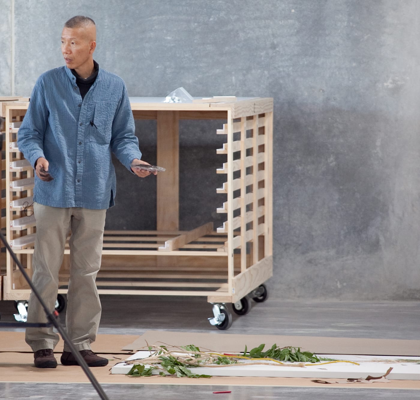 Cai Guo-Qiang stands beside a paper work in progress at the Museum of Fine Arts, Houston in 2010, with plant material and drawing elements laid out before ignition.