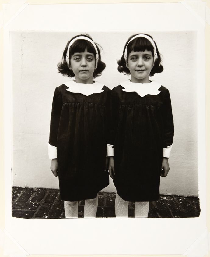 Diane Arbus's photograph Identical Twins, Roselle, New Jersey, showing two young girls in matching dark dresses and white headbands standing against a pale wall.