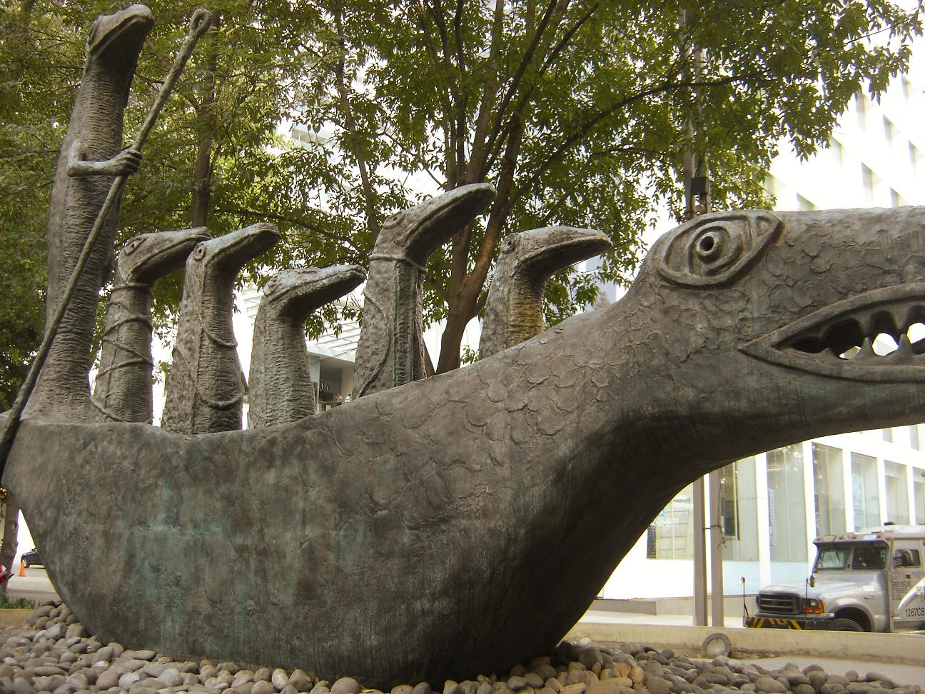 A real street photograph of Leonora Carrington's bronze crocodile sculpture, with several upright crocodile figures riding inside a large crocodile-shaped boat.
