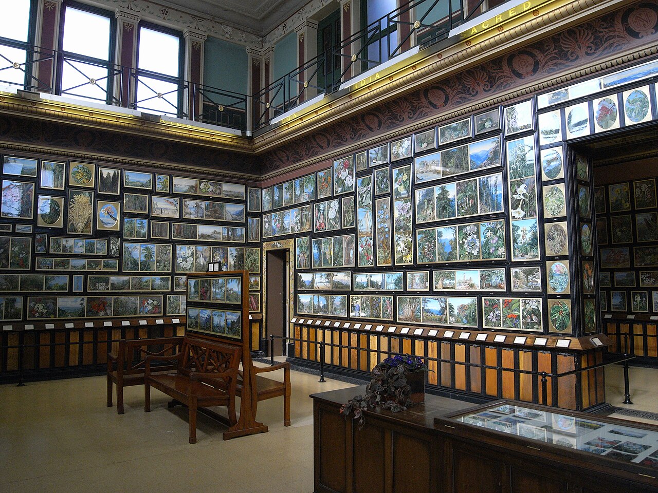 Interior photograph of the Marianne North Gallery at Kew Gardens, with dense rows of botanical paintings covering the walls.