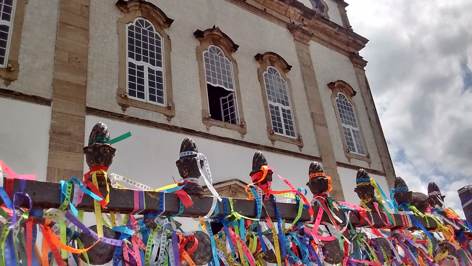 Hundreds of narrow, brightly coloured Bonfim ribbons tied to the dark iron rail in front of the white-tiled Basilica in Salvador.
