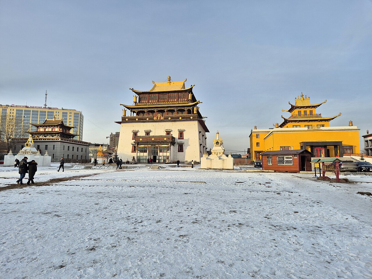 Gandantegchinlen Monastery in Ulaanbaatar, with golden temple roofs, a snow-covered courtyard, and visitors crossing the open ground.