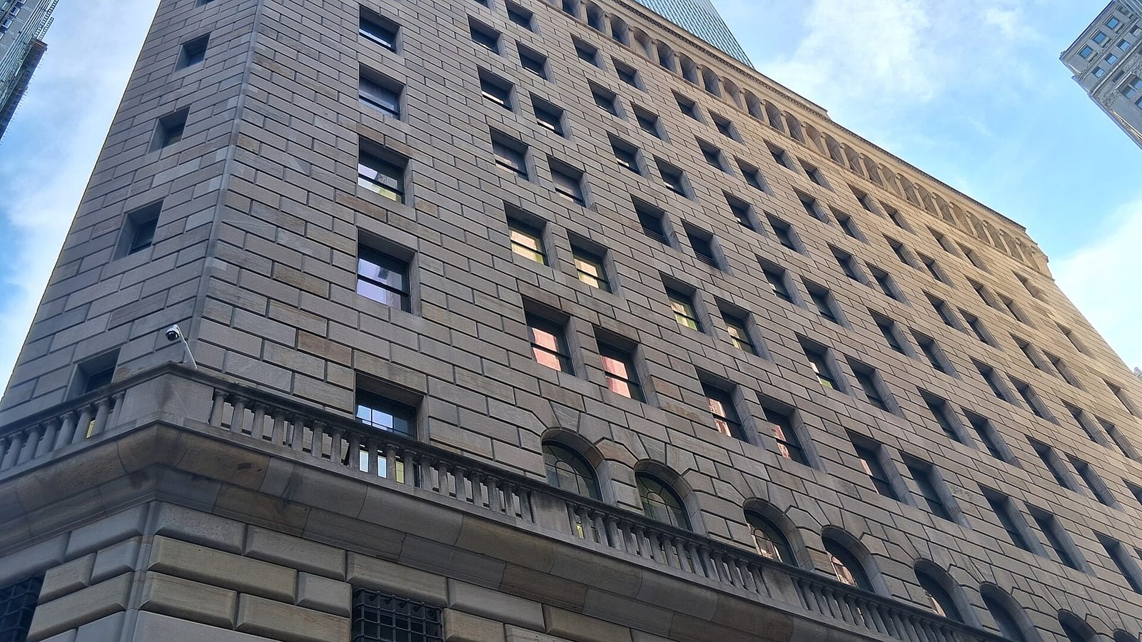 Street-level view of the rusticated stone facade of the Federal Reserve Bank of New York in Lower Manhattan.