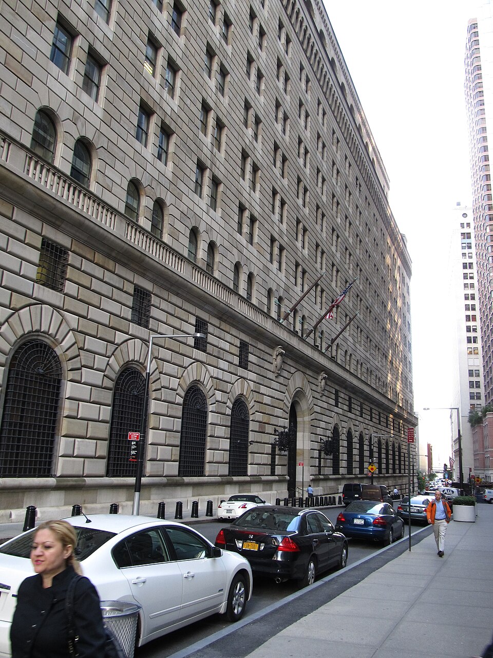 The fortress-like stone facade of the Federal Reserve Bank of New York at 33 Liberty Street in Manhattan, photographed from street level.