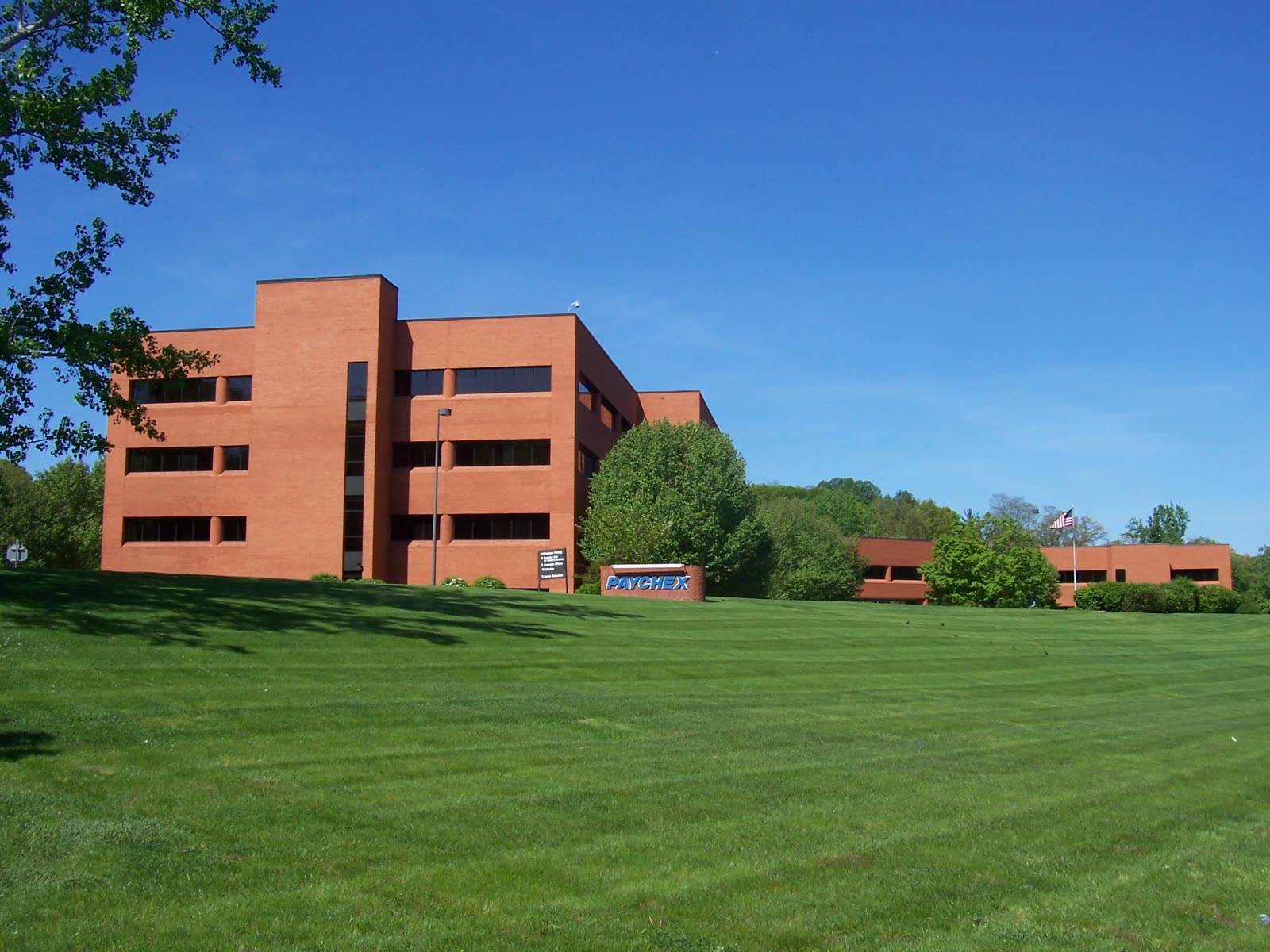 Paychex headquarters in Penfield, New York, photographed from across a lawn on a clear day.