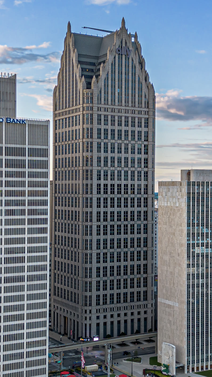 从高处望向底特律市中心石材外墙的 Ally Detroit Center 摩天楼，以及楼顶的 Ally 标志。