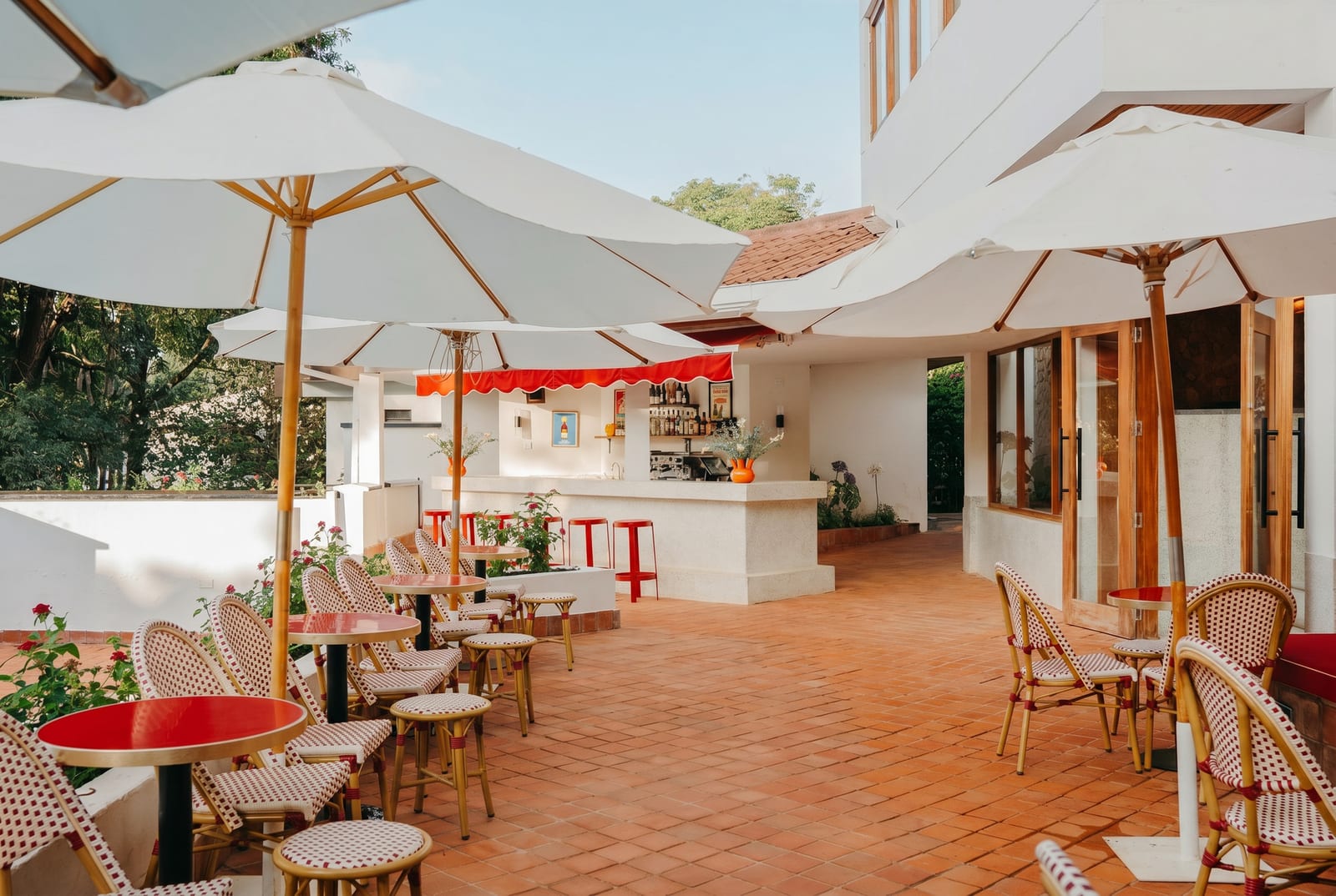 内罗毕 Bistro Lolo 洒满阳光的露台上，摆着红色咖啡桌、编织椅与白色遮阳伞，一旁是开放式酒吧。