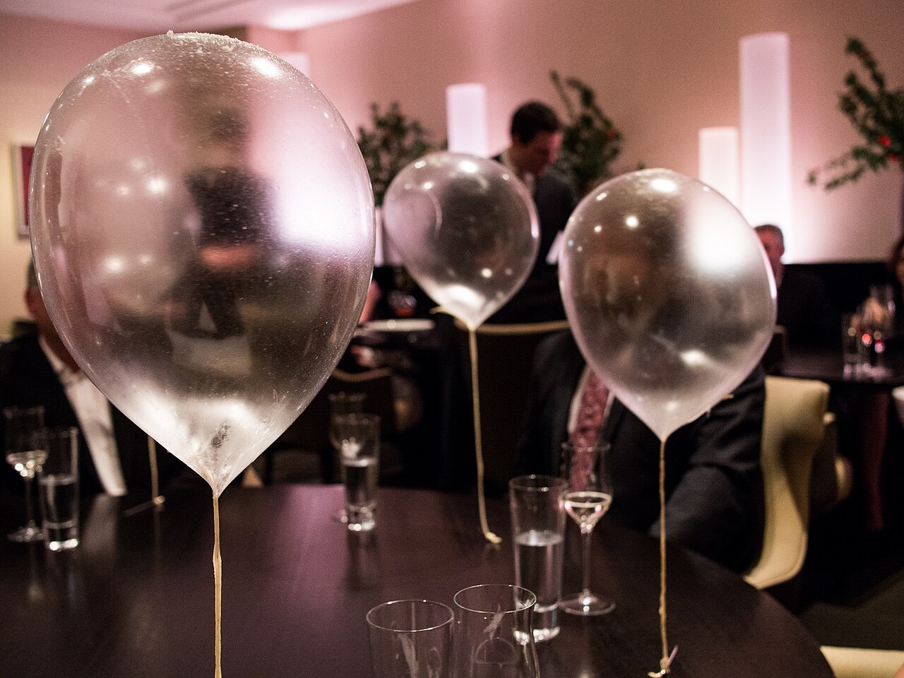 A translucent edible helium balloon course at Alinea, floating from a thin apple string above a dining table.