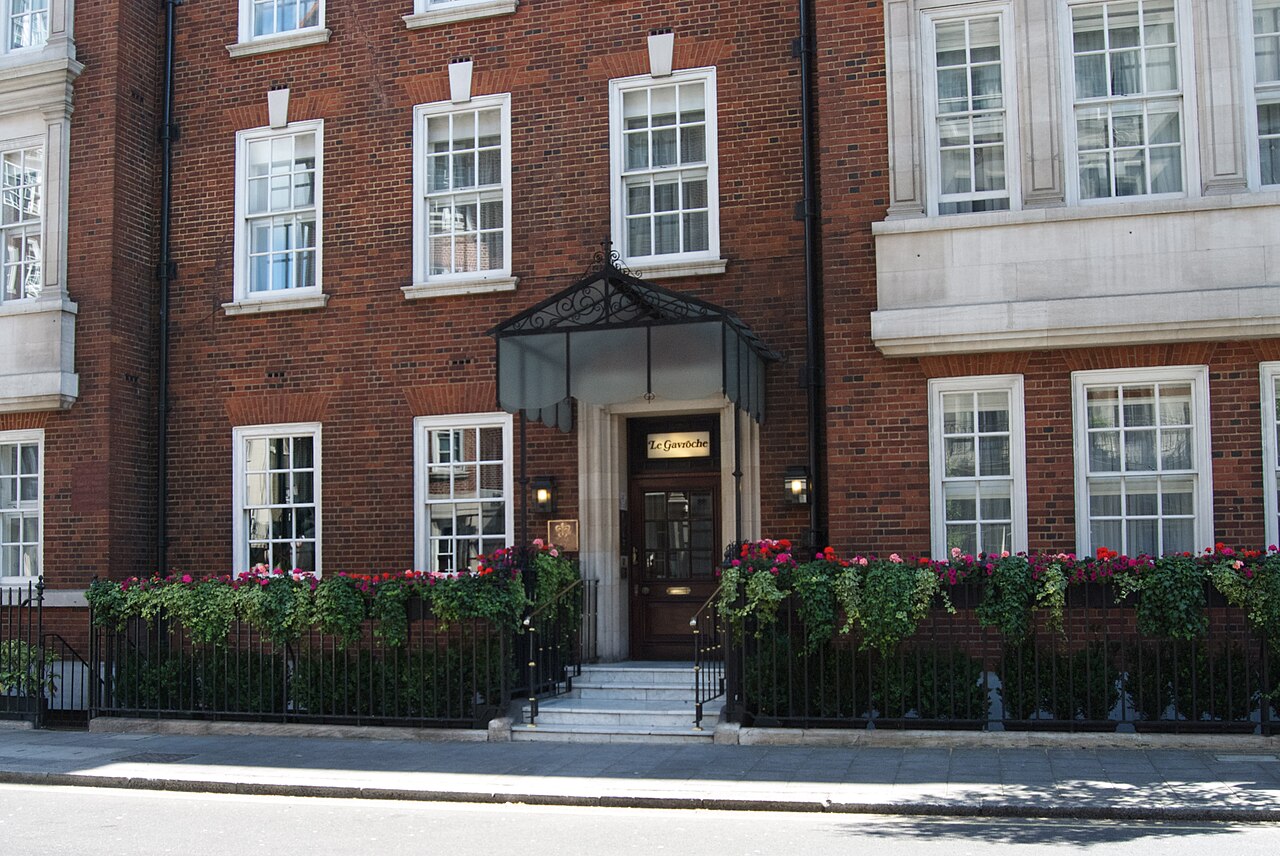 伦敦 Upper Brook Street 上 Le Gavroche 的砖砌 Mayfair 门面，入口两侧有花。