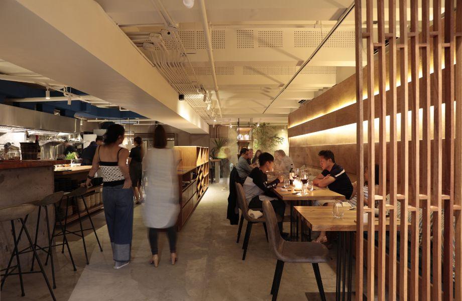 马卡蒂 Metiz 狭长的餐厅空间，食客坐在厨师吧台和开放式厨房旁的餐桌边。