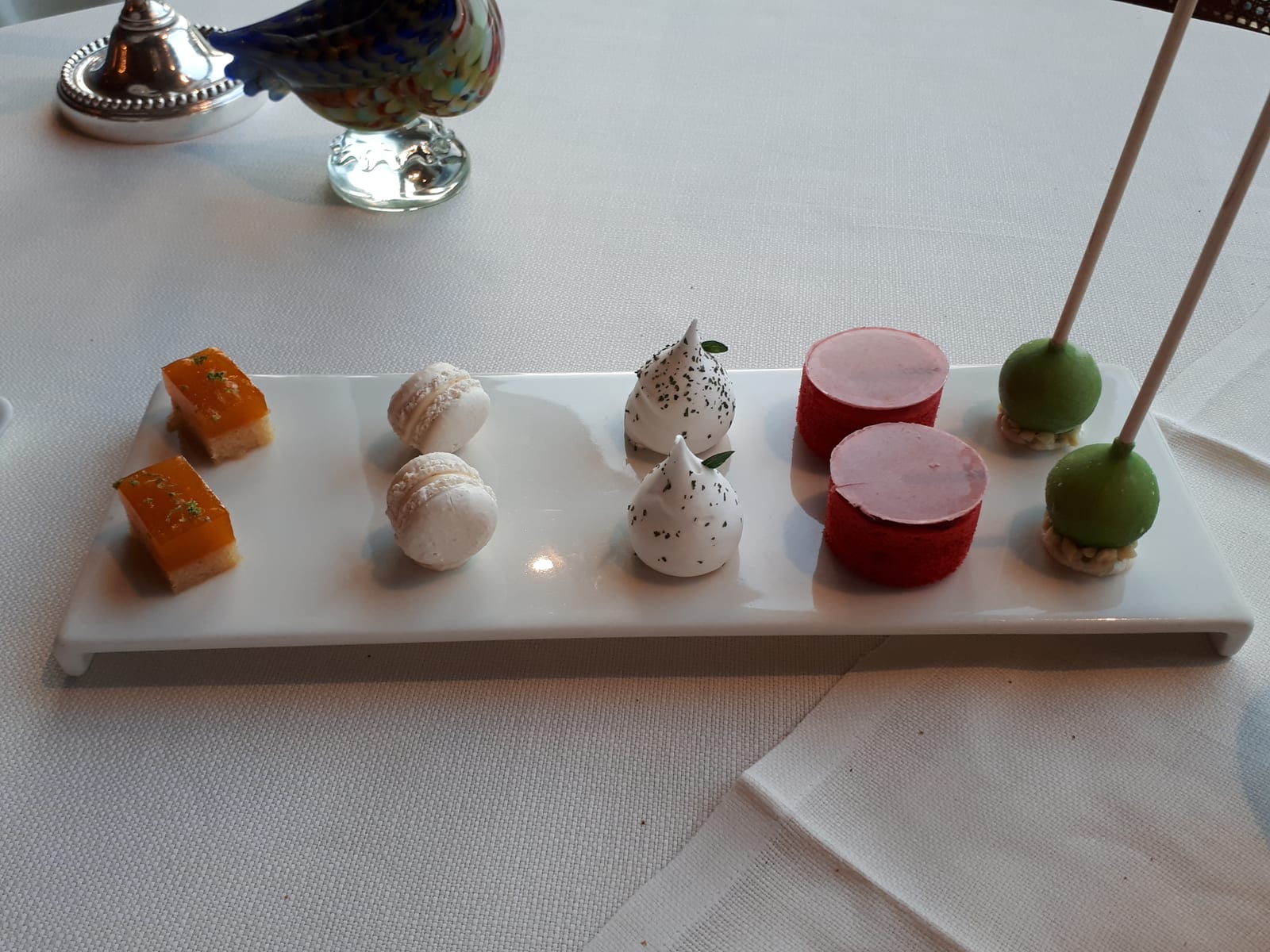 La Tour d'Argent 一只白色长方盘上的小型 mignardises，包括马卡龙、蛋白霜、果冻软糖和棒棒糖式小甜点。