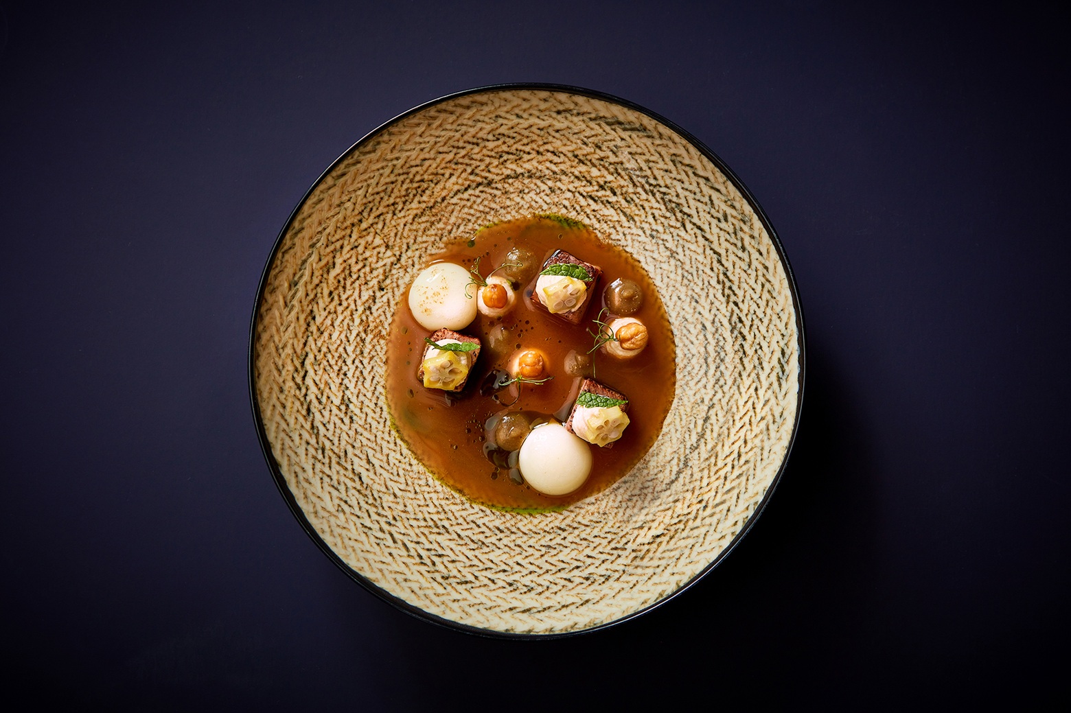 Renommée’s Etchmiadzin soup arranged as chickpeas, okra, small vegetable-and-meat components, and pale spheres in amber broth.