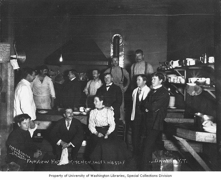 A chef and hotel staff gathered inside the working kitchen of the Fairview Hotel in Dawson, Yukon, around 1900.