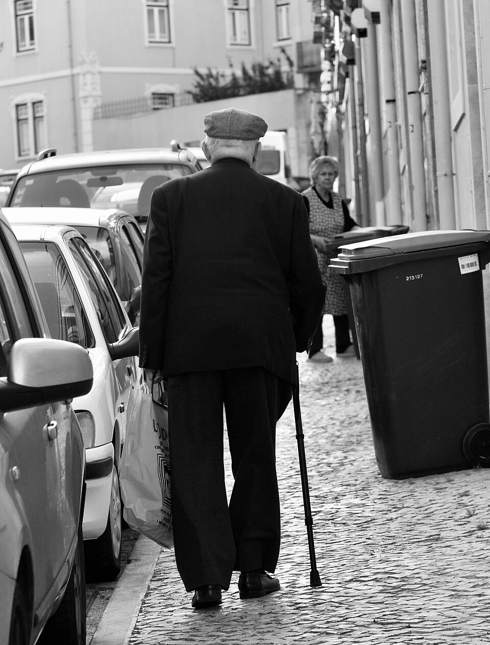 An older man walking on a Lisbon street with a single-point cane.