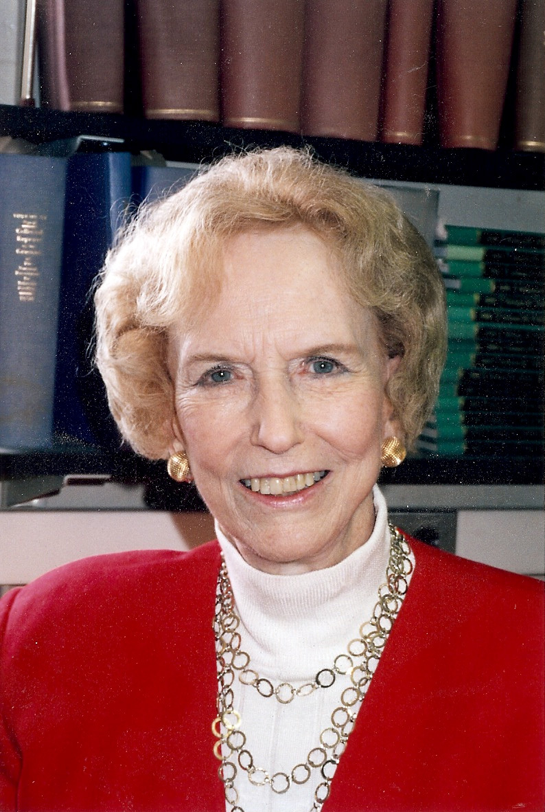 Color portrait photograph of epidemiologist Dorothy Horstmann seated in her Yale office in front of shelves of bound journals.
