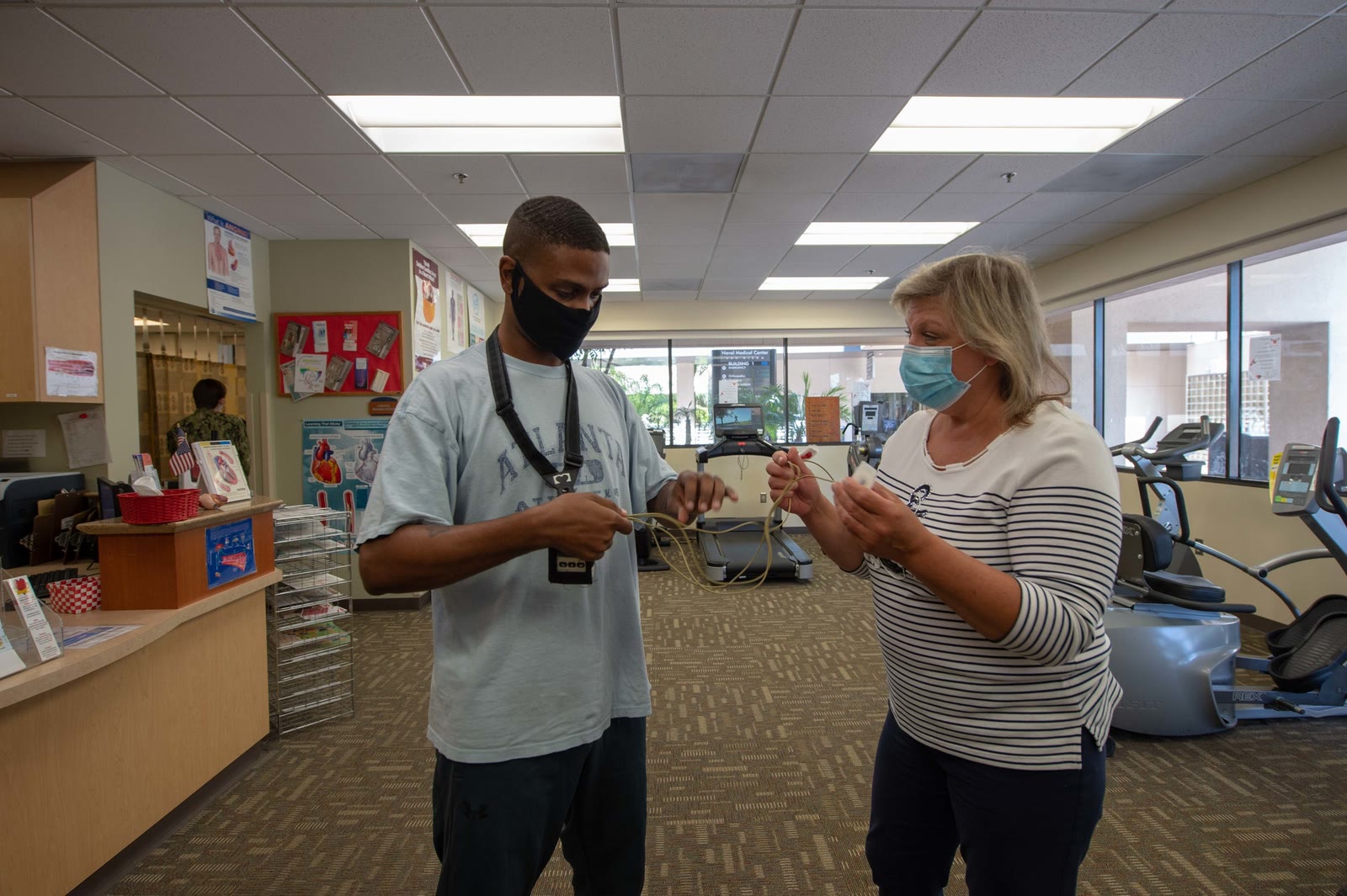 A nurse helps a patient put on a telemetry monitor in a cardiac rehabilitation clinic.