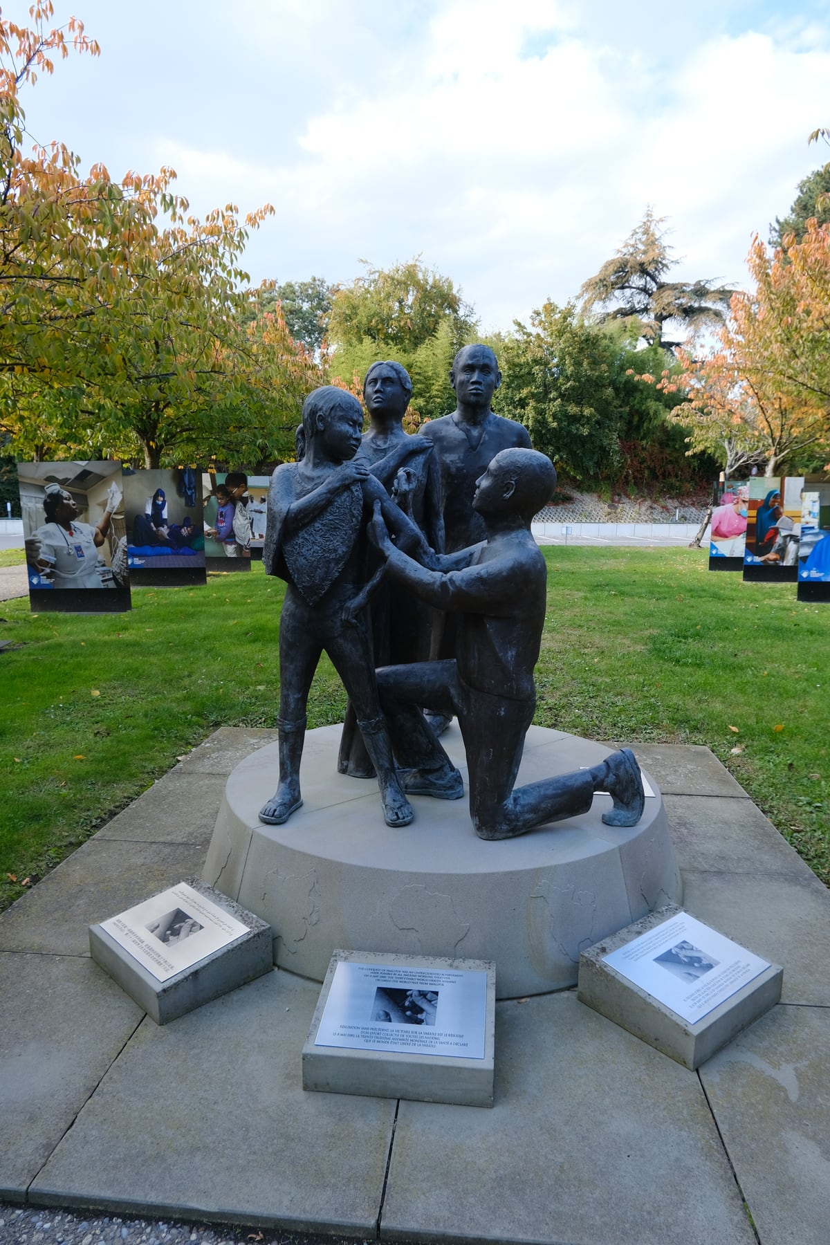 Photograph of the bronze smallpox eradication memorial showing a health worker vaccinating a child outside World Health Organization headquarters.