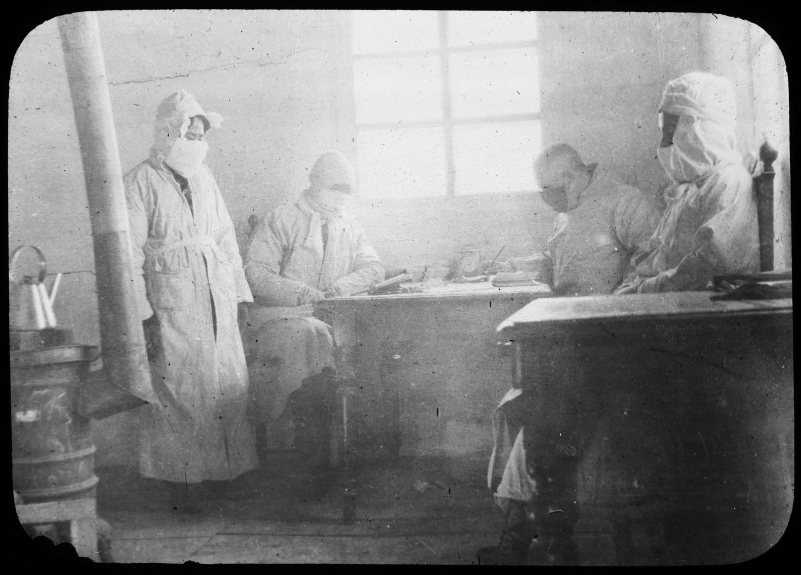 Black-and-white archival photograph of public-health workers gathered as Dr. Graham Aspland receives field reports in Fuchiatien during the 1910–1911 Manchurian plague epidemic.