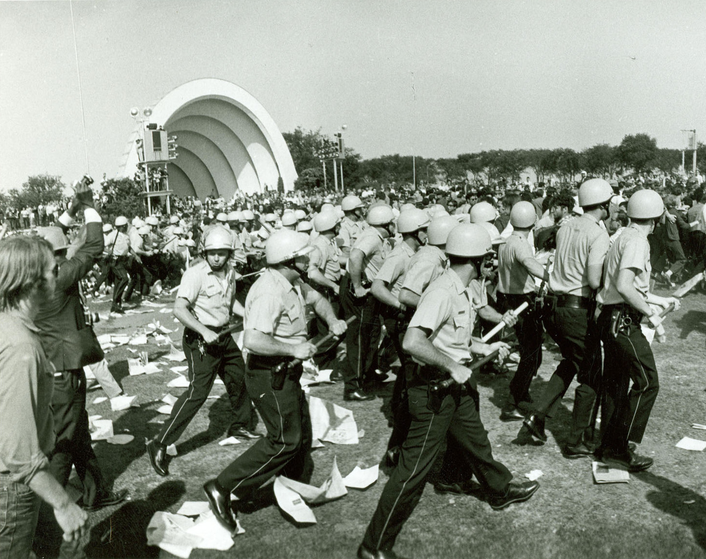 一张黑白档案照片，戴头盔的芝加哥警察在 1968 年民主党全国代表大会期间穿过格兰特公园，向示威者推进。