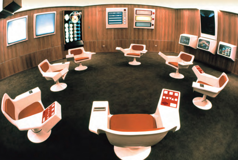 Cybersyn 项目作战室的一张档案照片，可见白色旋转椅、木墙板、显示屏和控制面板。