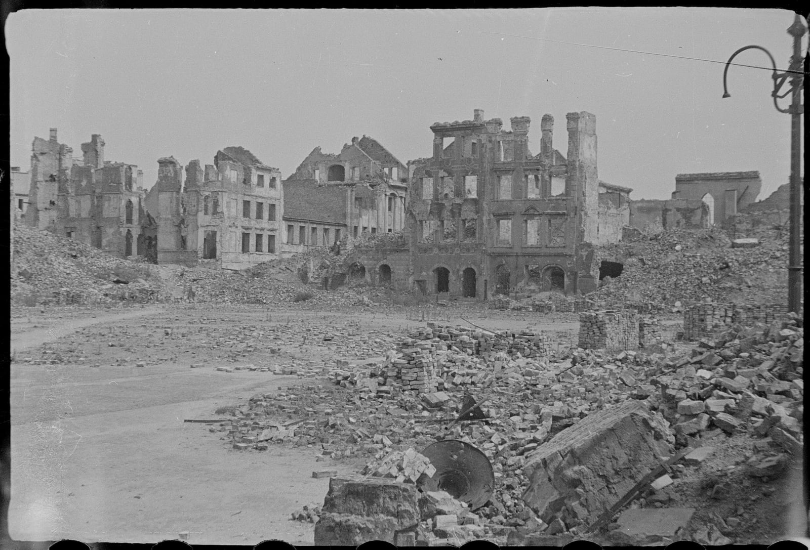 Black-and-white archival photograph of Warsaw's Old Town Market Square reduced to roofless facades and heaps of brick in 1945 or 1946.