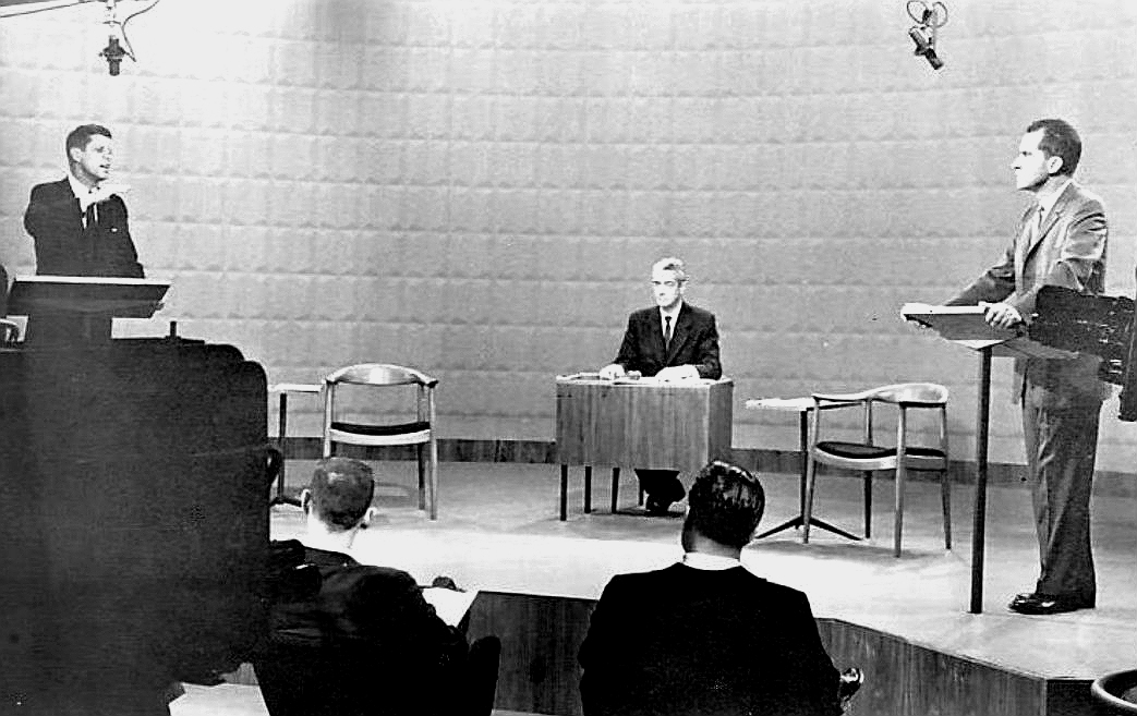 Black-and-white archival photograph of John F. Kennedy and Richard Nixon standing at lecterns during the first 1960 presidential debate in a Chicago television studio.