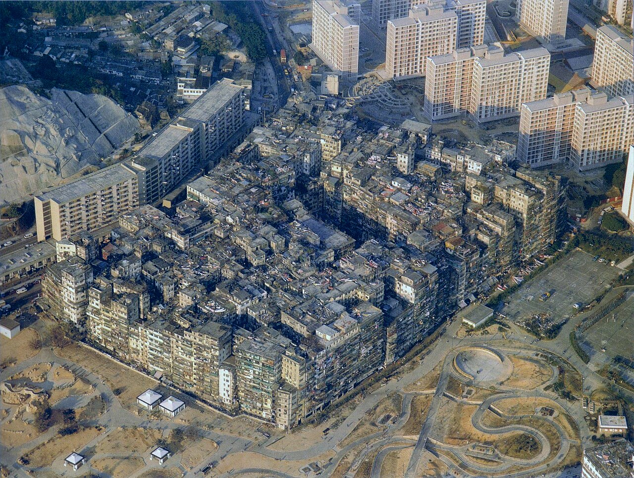 1989 年九龙寨城航拍照片，可见密集的低层与中层建筑群，周边是较新的高层屋邨和道路。
