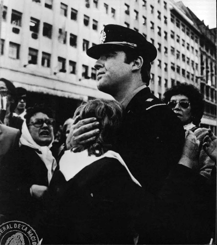 1982年的一幅黑白照片中，一名阿根廷警务官员抓住一位五月广场母亲，四周是戴着白色头巾的妇女。