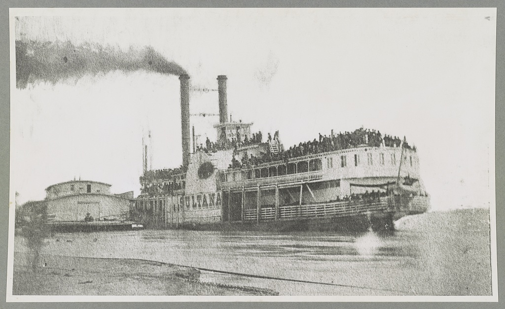 Grainy black-and-white archival photograph of the steamboat Sultana at Helena, Arkansas, on April 26, 1865, with recently released Union prisoners crowded across its decks.