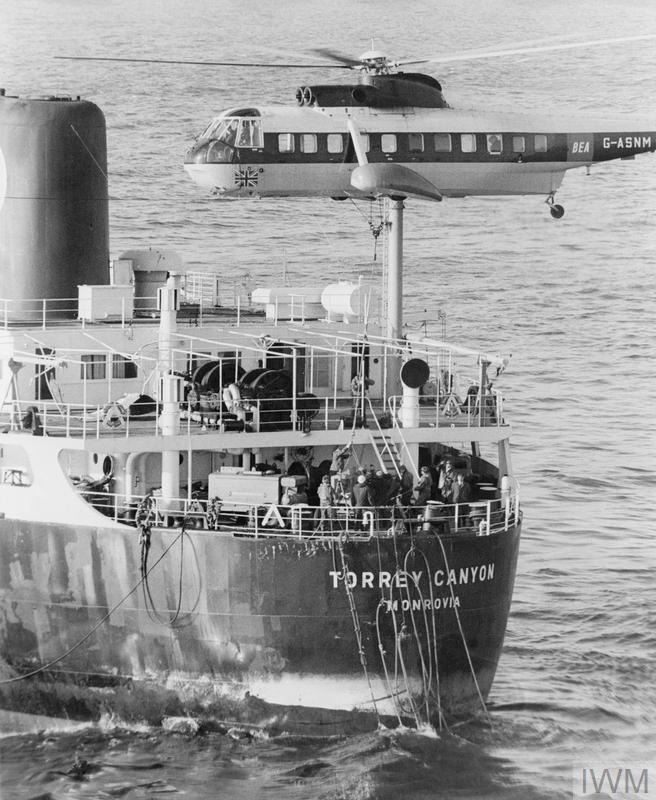 Archival black-and-white photograph of a helicopter lowering salvage equipment onto the stranded Torrey Canyon while workers gather on deck in March 1967.