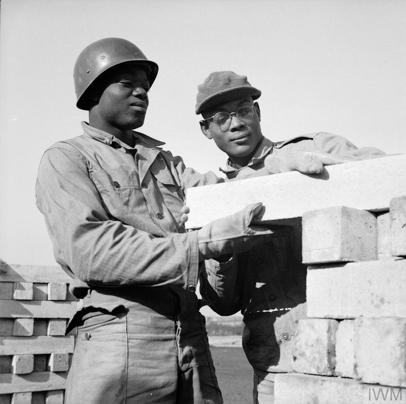 一张 1943 年战时黑白照片，两名美国黑人士兵在英国铁路轨道旁工作。