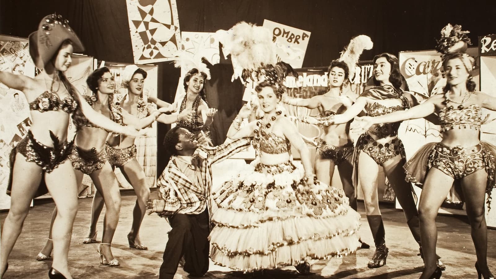 在《Carnaval Atlântida》的《No Tabuleiro da Baiana》歌舞段落中，Grande Otelo 跪在身穿华丽巴伊亚女性传统服饰的 Eliana Macedo 身旁，四周围着伴舞演员。
