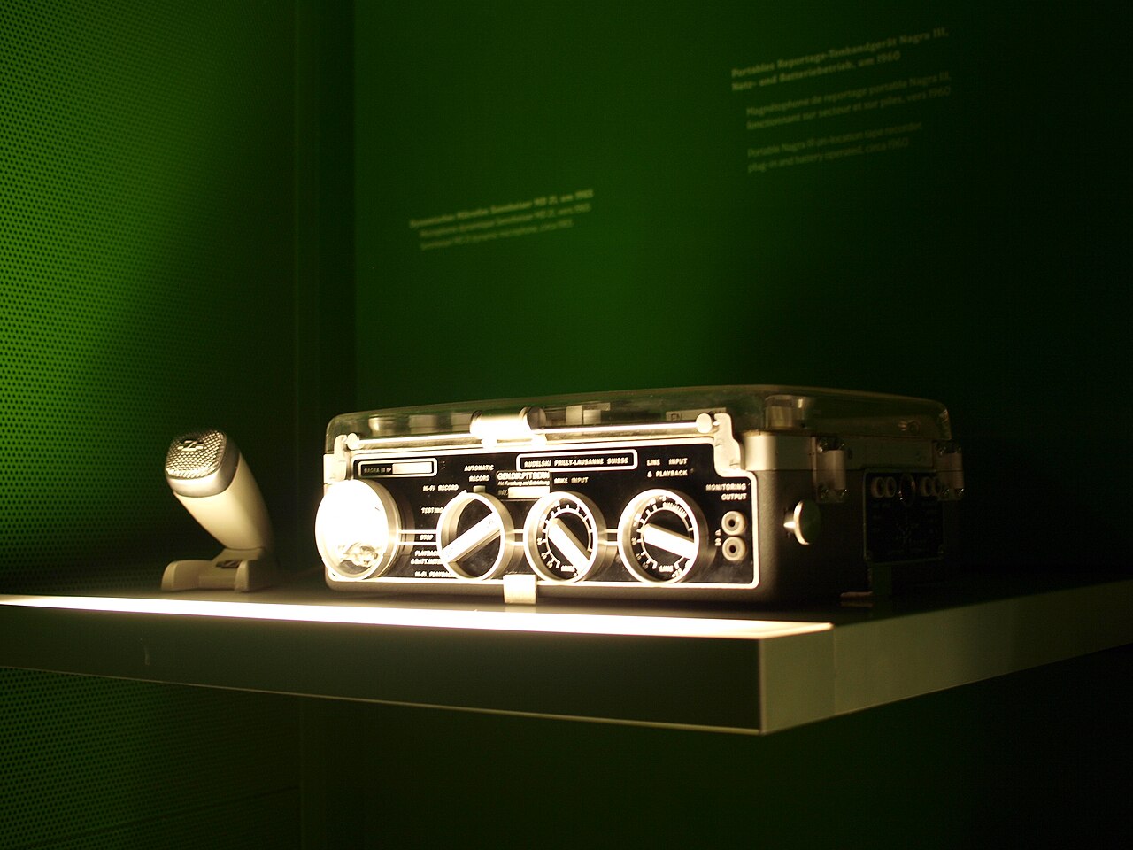 一张 Nagra III 便携式开盘录音机的近距离照片，画面可见盘带、modulometer、开关和金属机身。
