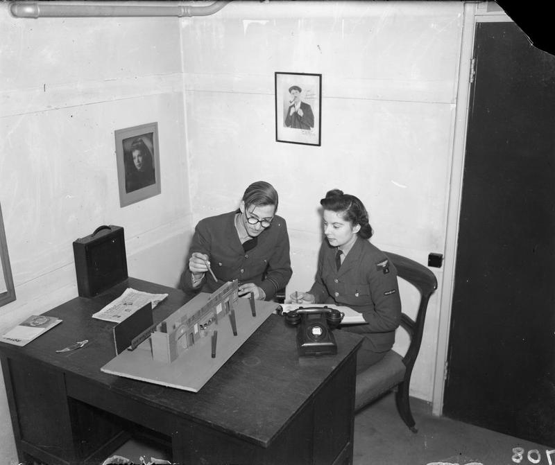 Film director J. E. Boulting and continuity worker Doreen North sit at a table reviewing the setup of a railway-station shot for Journey Together.