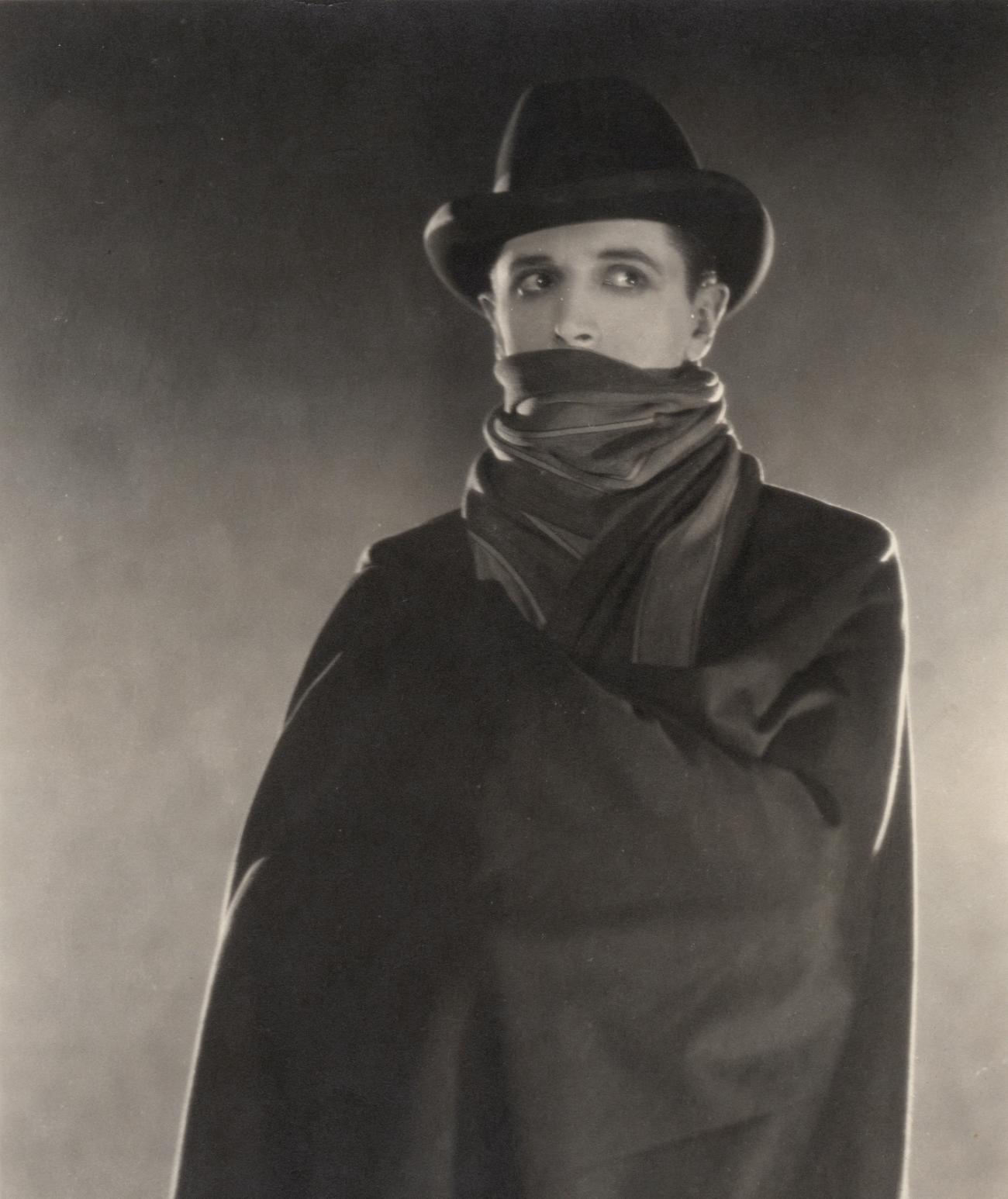 Black-and-white archival still from The Lodger showing Ivor Novello in a dark hat and scarf, his eyes turned sideways above the wrapped cloth.
