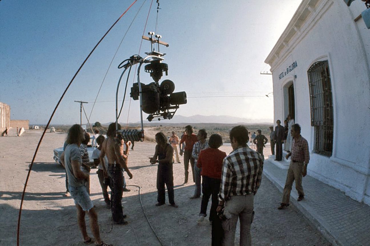 A gyro-stabilized motion-picture camera hangs from a cable above cast and crew beside the white hotel set built for the final sequence of The Passenger.